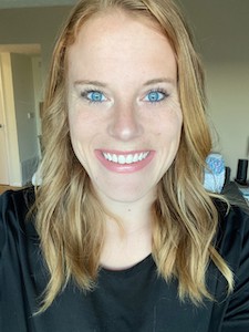 Selfie of testimonial writer, Libbi. She is a white woman with blue eyes and strawberry blonde hair. She is smiling at the camera.