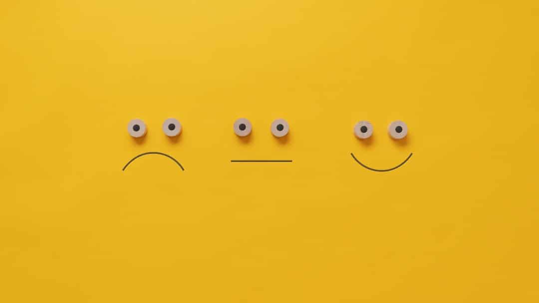 Three simple faces drawn on a yellow background: frowning, neutral, and smiling.